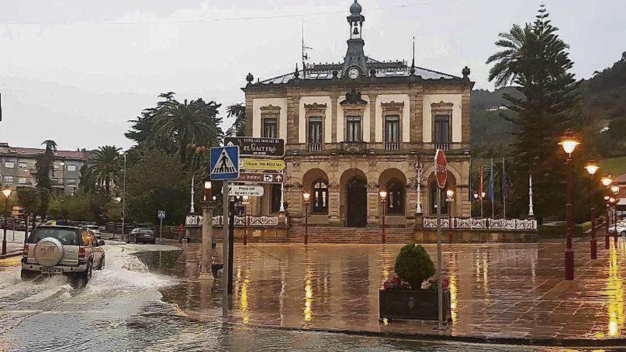 Un coche ante el Ayuntamiento de Villaviciosa, con la vía llena de agua.