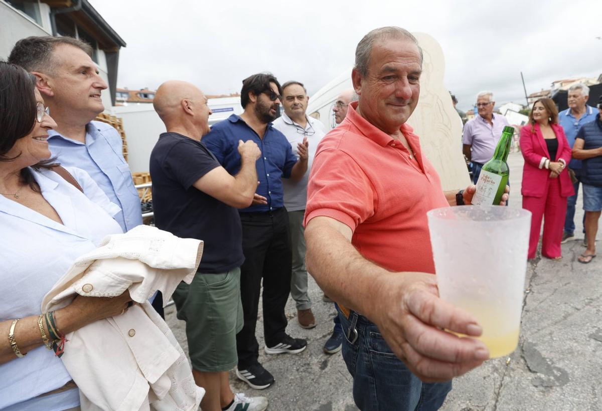 Sobre estas líneas, el patrón mayor de la Cofradía de Llanes, Ángel Batalla, brinda con sidra por el premio. A la izquierda, vecinos celebrando la concesión del galardón junto a la rula. | LUISMA MURIAS