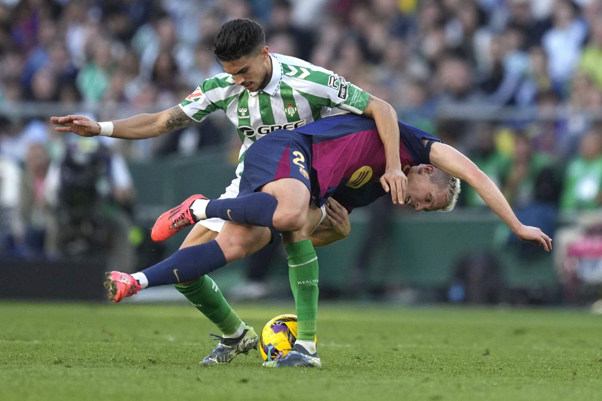 Barcelona's Dani Olmo, right, challenges for the ball with Betis' Marc Bartra during a Spanish La Liga soccer match between Betis and Barcelona at the Benito Villamarin stadium in Seville, Spain, Saturday, Dec. 7, 2024. (AP Photo/Jose Breton)