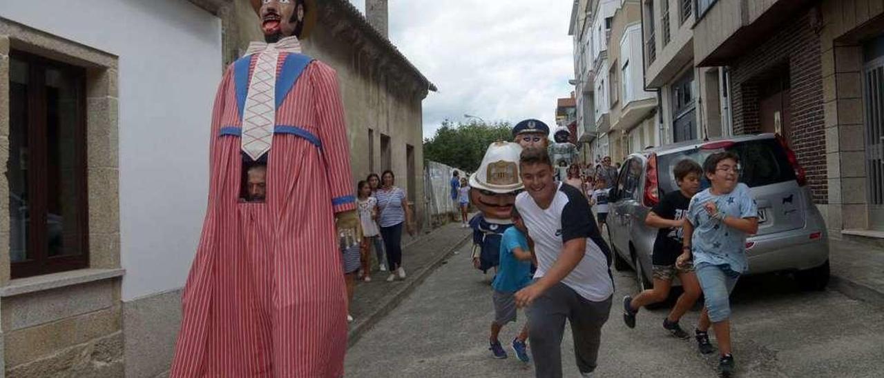 Los niños persiguen al gigante &quot;Papamoscas&quot; por las calles de Carril.  // Noé Parga