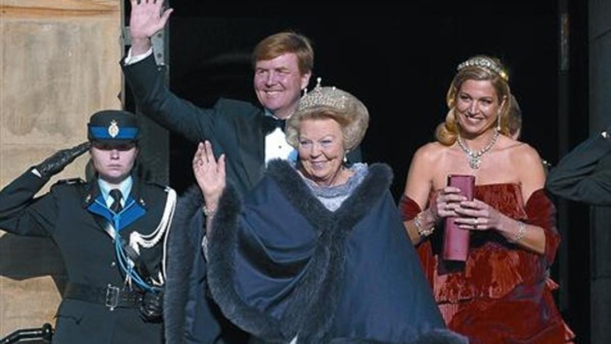 La reina Beatriz, junto al príncipe Guillermo y su esposa, Máxima, saludan a los ciudadanos holandeses, ayer.