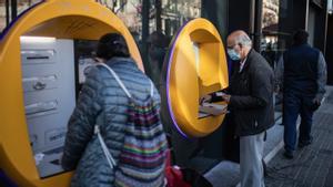 Una persona mayor retira dinero del cajero de un banco.