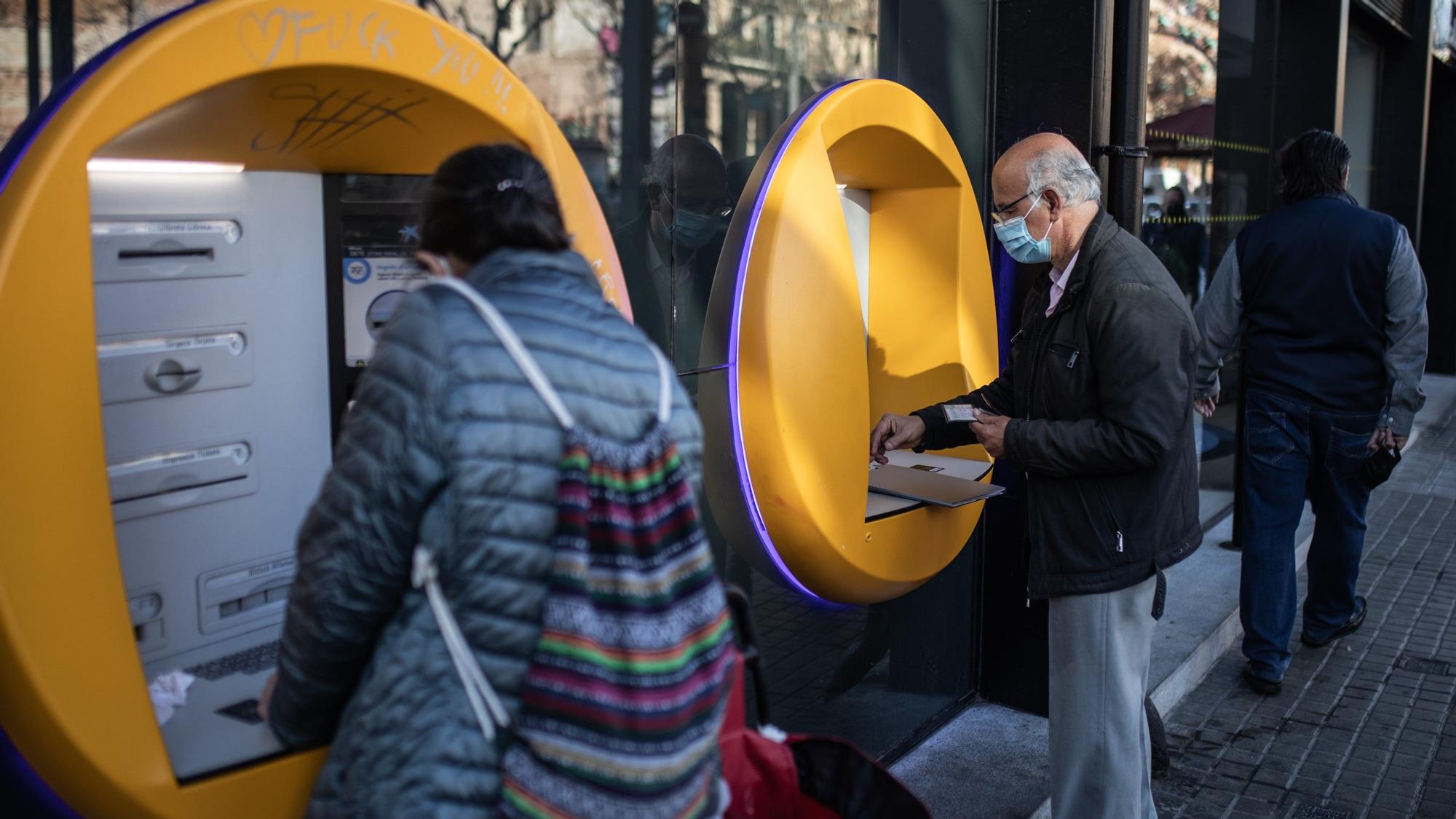 Una persona mayor retira dinero del cajero de un banco.