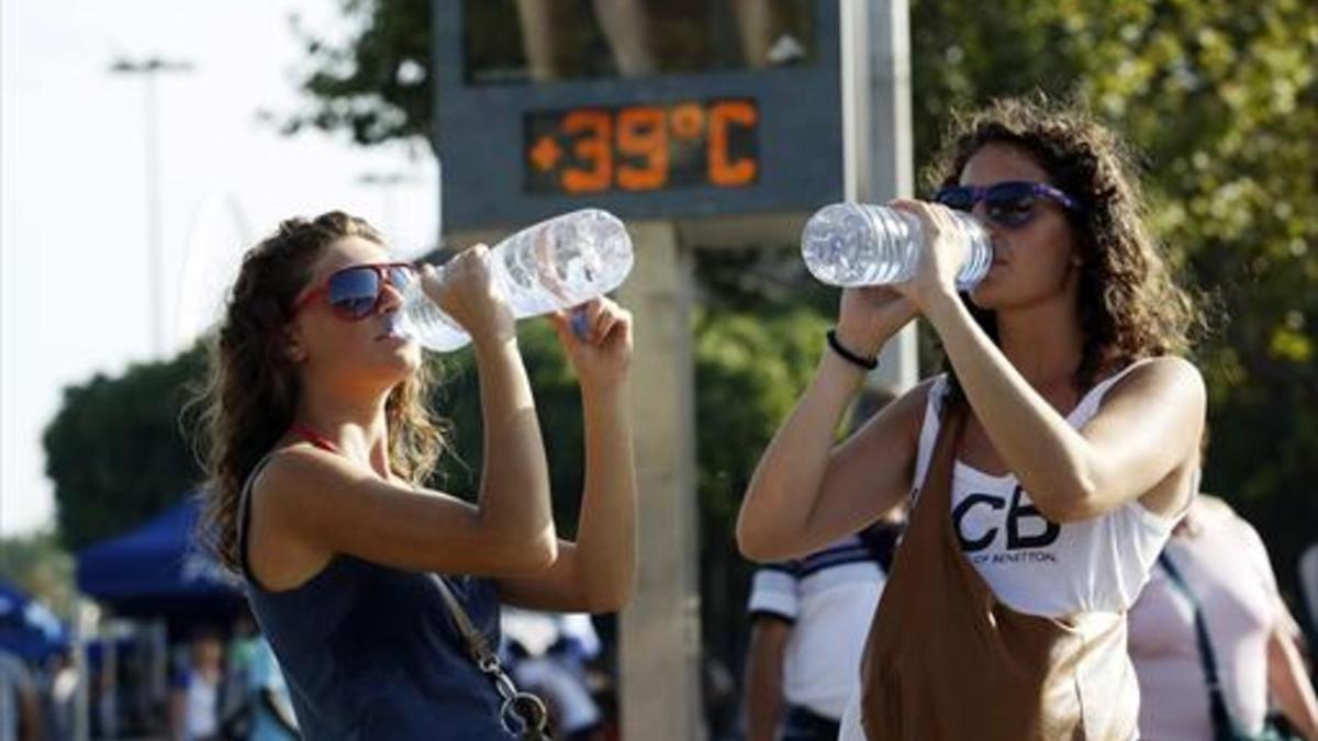 Dos turistas se hidratan en Barcelona para combatir el calor.