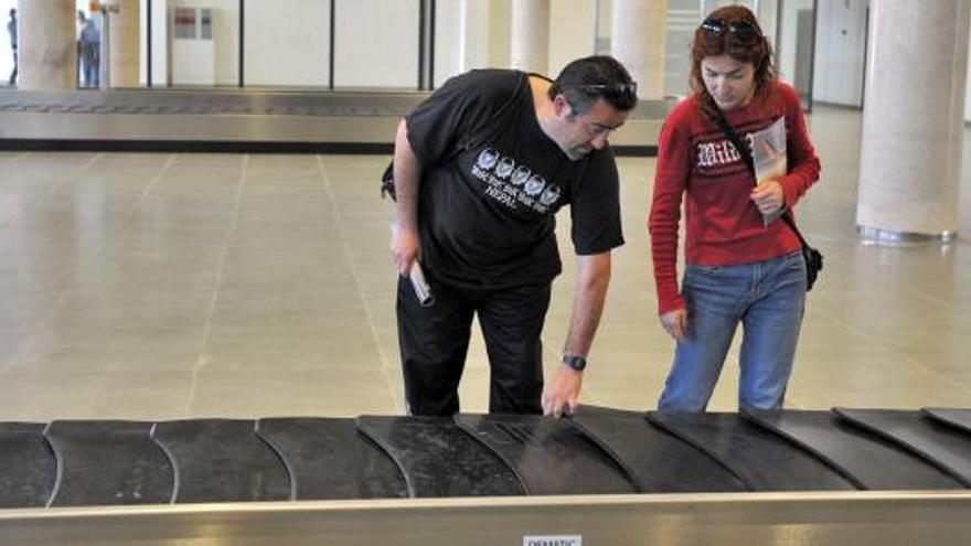 Una pareja mira la cinta portaequipajes del Aeropuerto de Castelló.