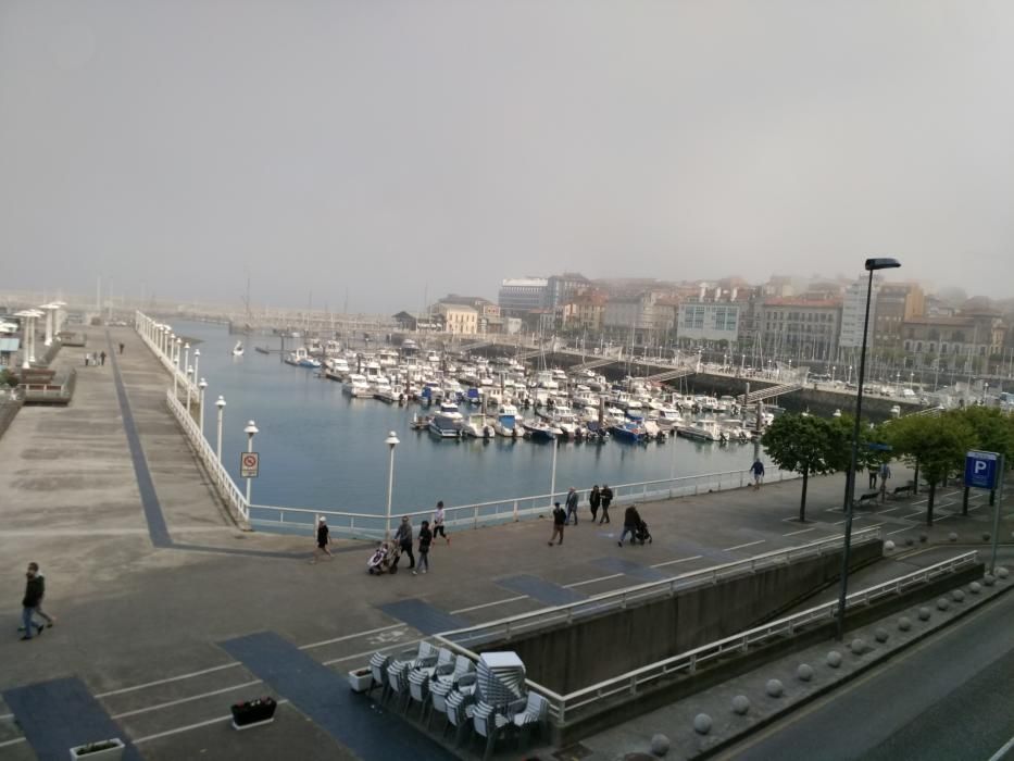 La bruma chafa el día de sol en la costa de Gijón.