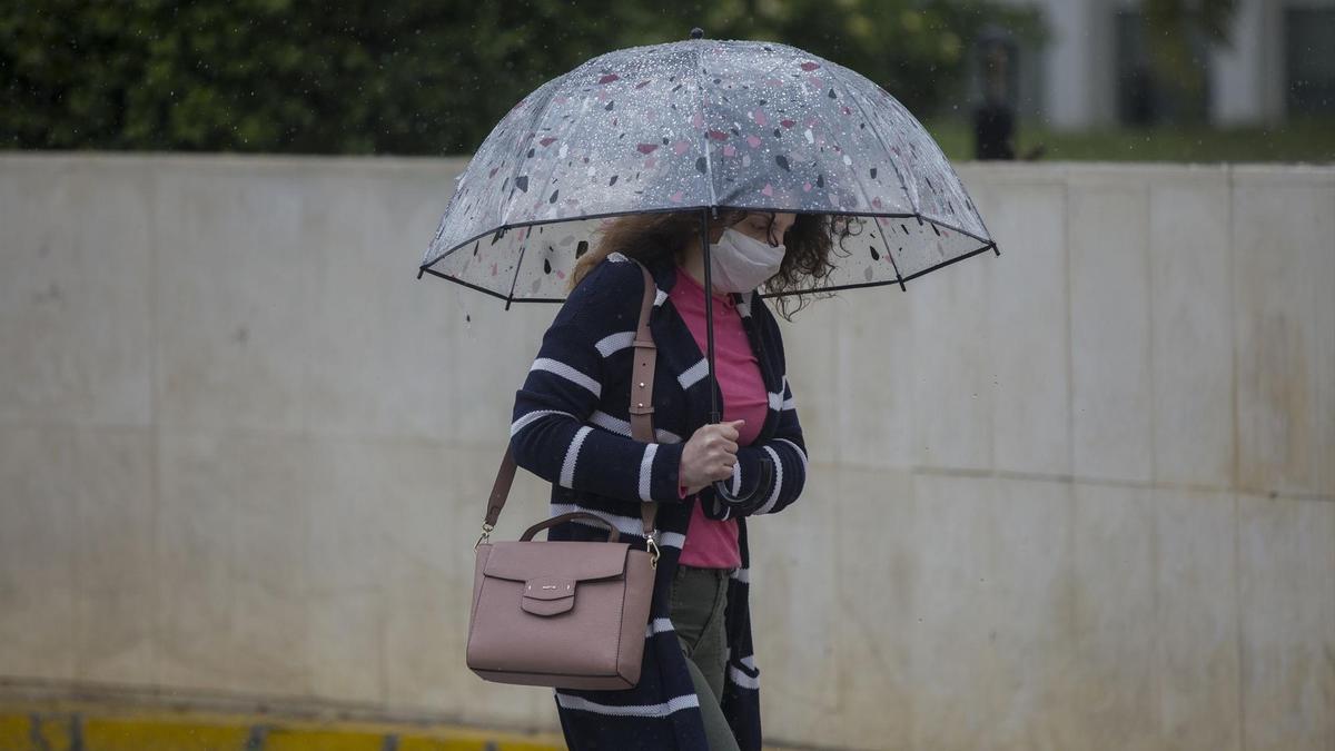 Archivo - Una mujer con paraguas y mascarilla en una imagen de archivo