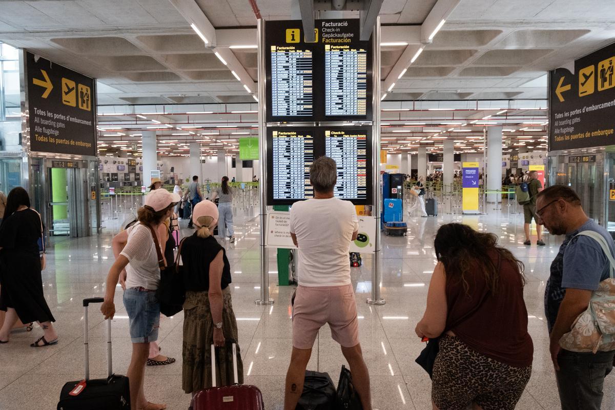 Pasajeros consultan los horarios electrónicos de los vuelos en la planta de facturación de equipajes