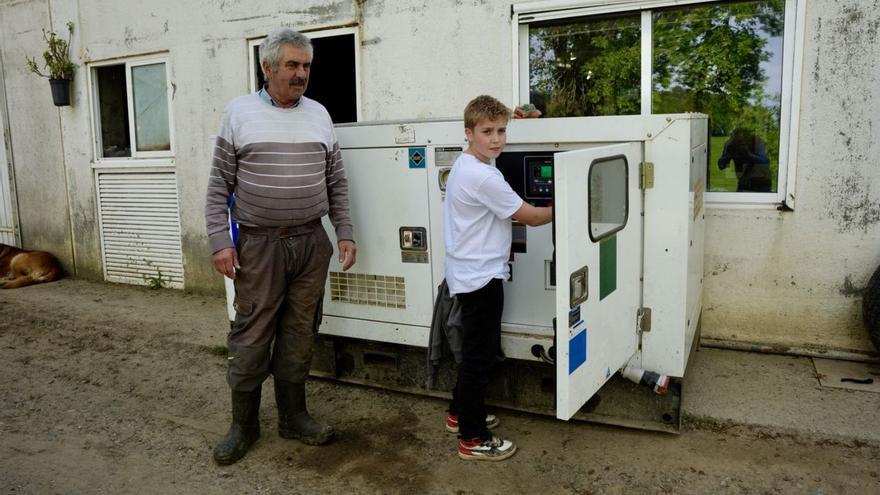 José Nogueira y su nieto ante un generador en su granja de Sello.
