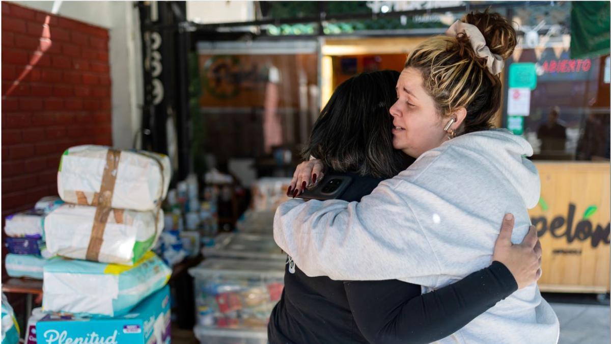 Dos mujeres se abrazan en un centro de recogida de material humanitario para Venezuela.
