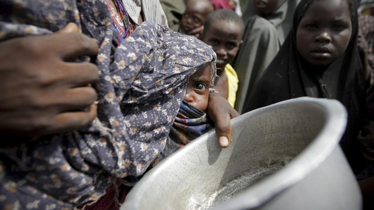 Una mujer con su bebé mientras hace cola para conseguir alimentos en un campamento para los desplazados de Mogadiscio (Somalia)