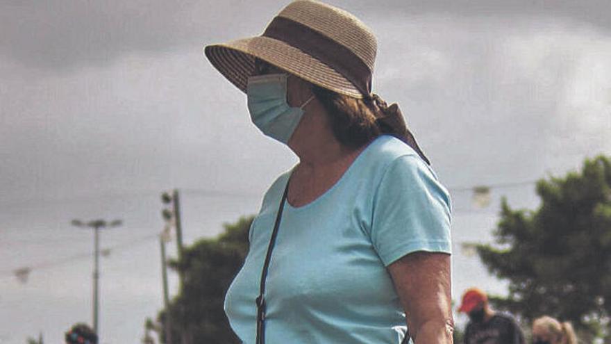 Una mujer con mascarilla camina por la plaza de España.