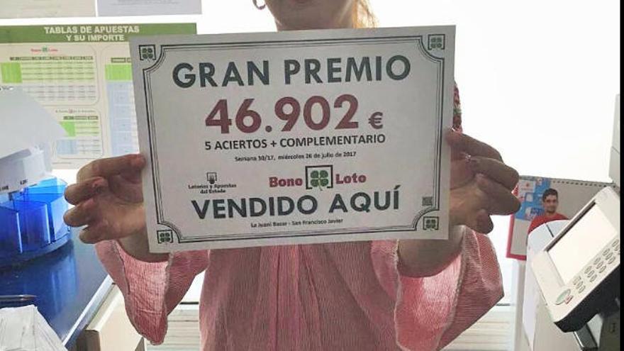 Una trabajadora del bazar con el cartel del premio de la Bonoloto.