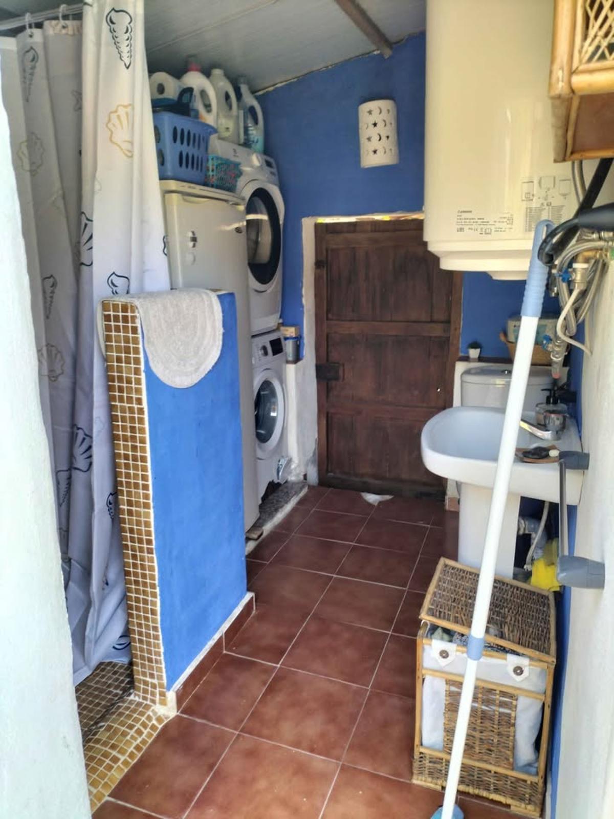 Imagen del baño exterior, con ducha y lavadora.