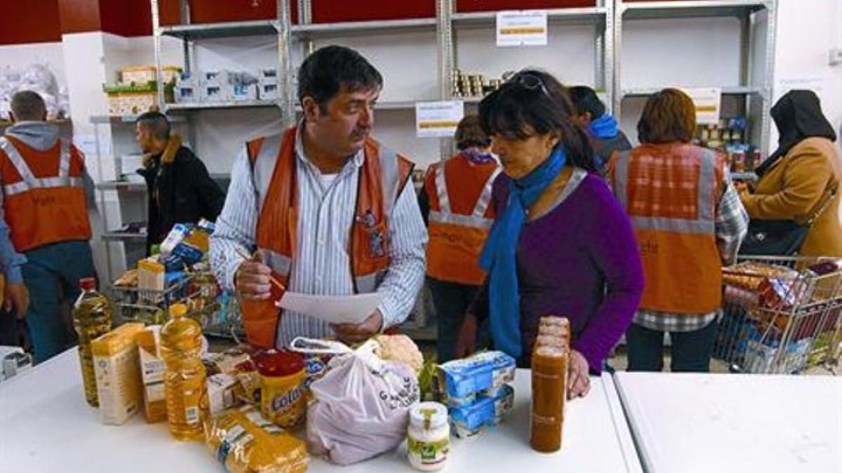 En el local 8 El voluntario José María Gallardo ayuda a María Dolores Segarra a recoger un lote, el miércoles.