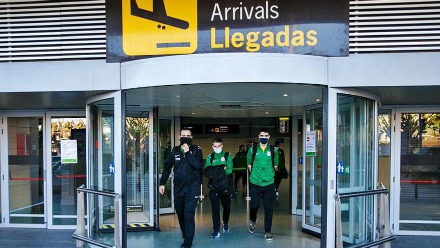 Un grupo de personas, con mascarilla, frente a la puerta de llegadas del aeropuerto de Ibiza.
