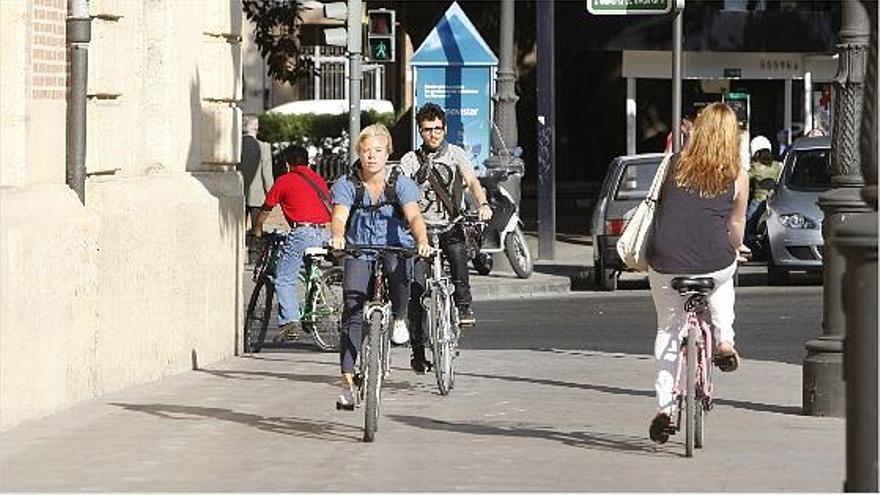 Ciclistas circulando ayer por la acera del Palacio de Justicia en la ciudad de Valencia.