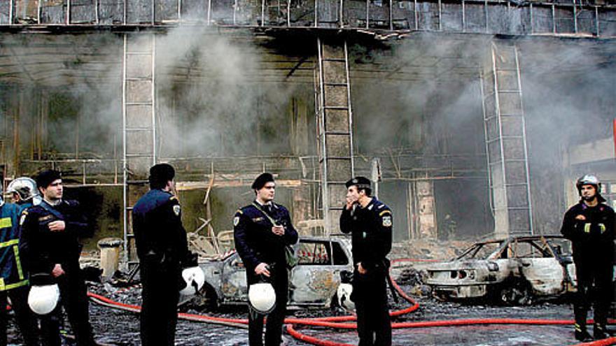 Varios policías y bomberos, desplegados en un edificio arrasado por las llamas, ayer en Atenas.