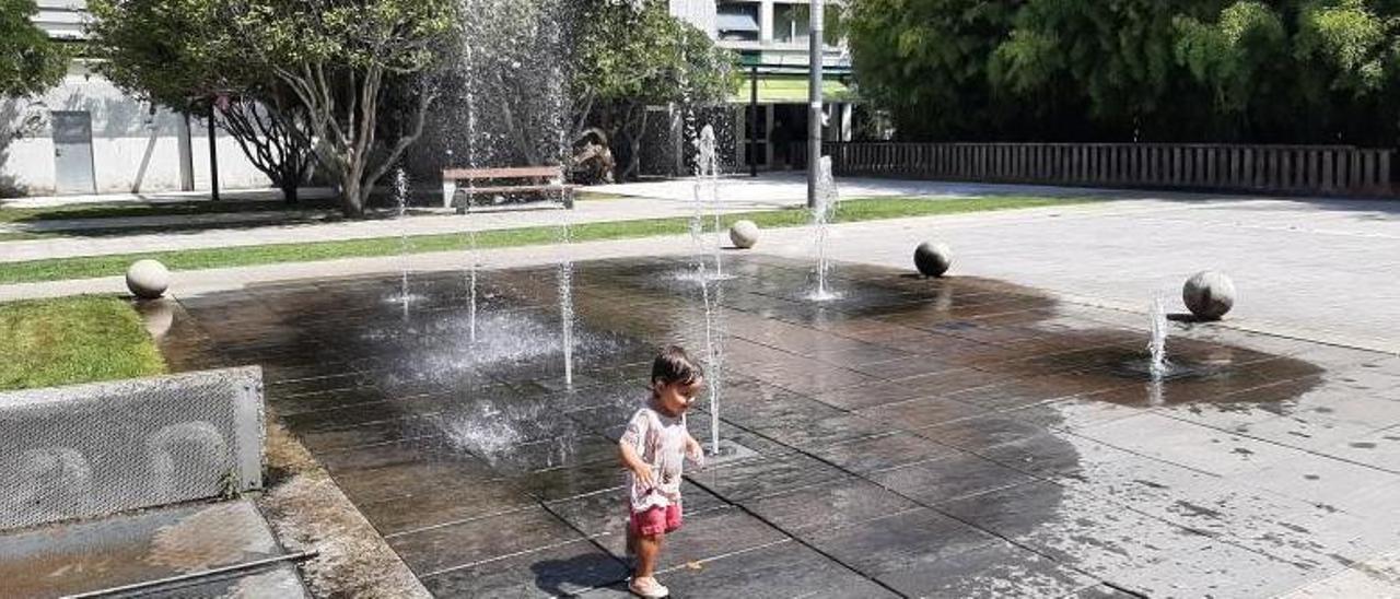 Una niña juega y se refresca en la fuente de la Praza Massó (Bueu), que funciona con un circuito cerrado. | // G.NÚÑEZ