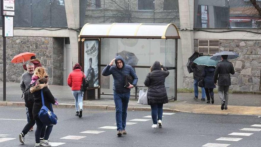 Un grupo de gente protegiéndose de la lluvia y el frío, ayer, en A Coruña.