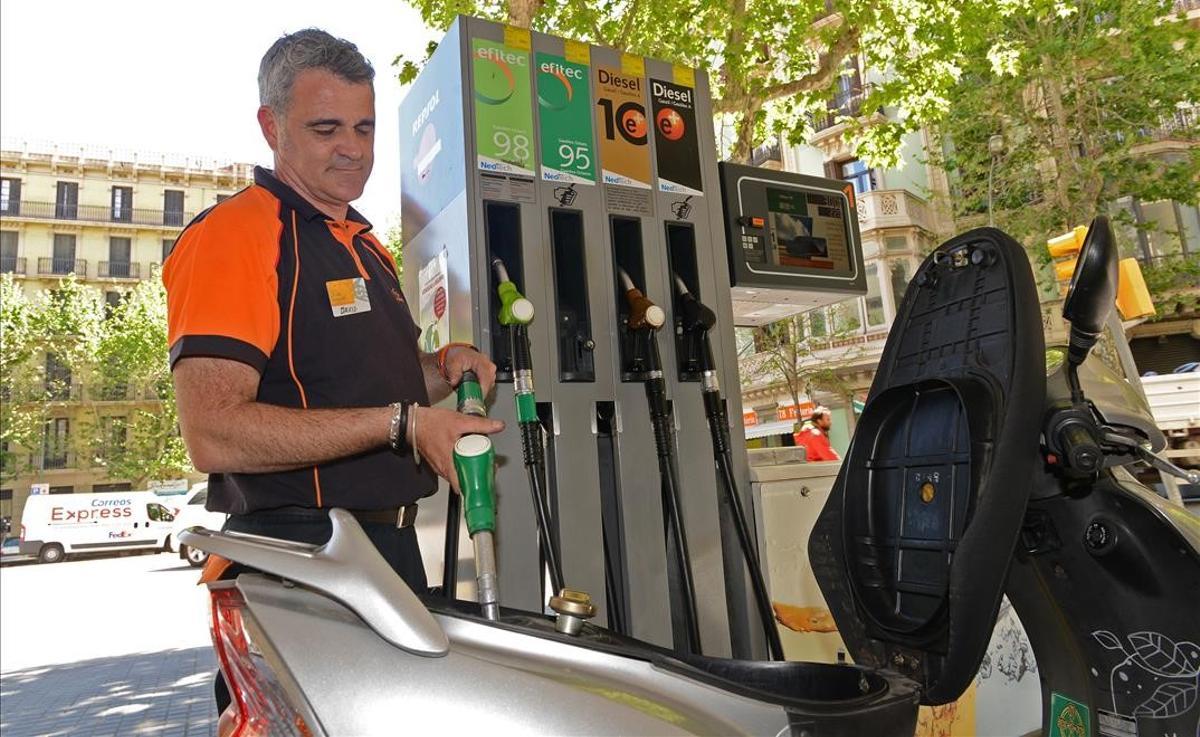 La energía acelera la inflación en España hasta el 2,2 % en abril. En la foto, un empleado de una gasolinera pone combustible en una moto, en Barcelona.