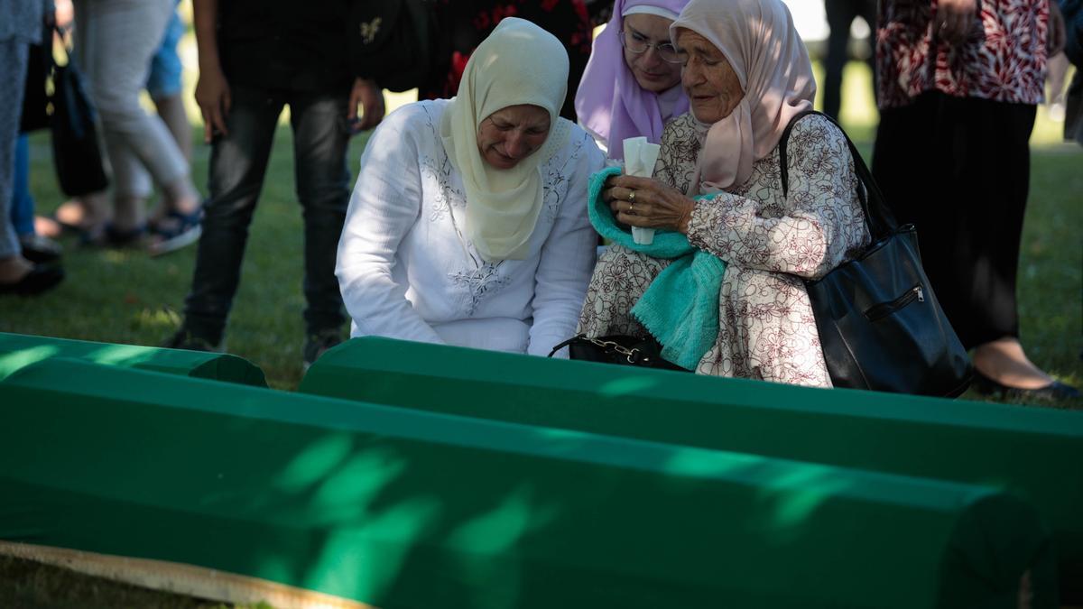 Mujeres musulmanas bosnias lloran sobre los ataúdes con los restos de las víctimas