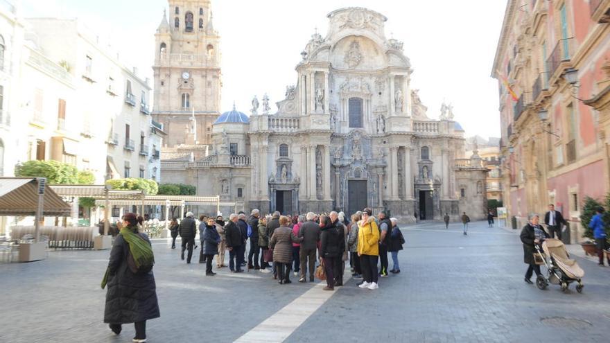 Un grupo de turistas atiende las explicaciones del guía en la plaza de la Catedral de Murcia.