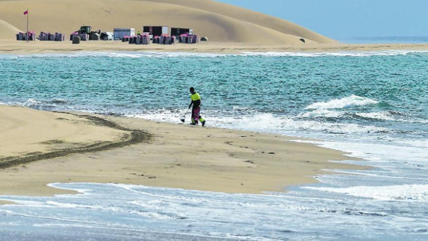 Un operario limpia la playa de Maspalomas, en el sur de Gran Canaria, vacía por el cierre turístico.