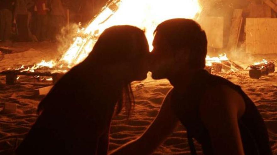 Una pareja se besa junto a una hoguera en la playa. / fran martínez