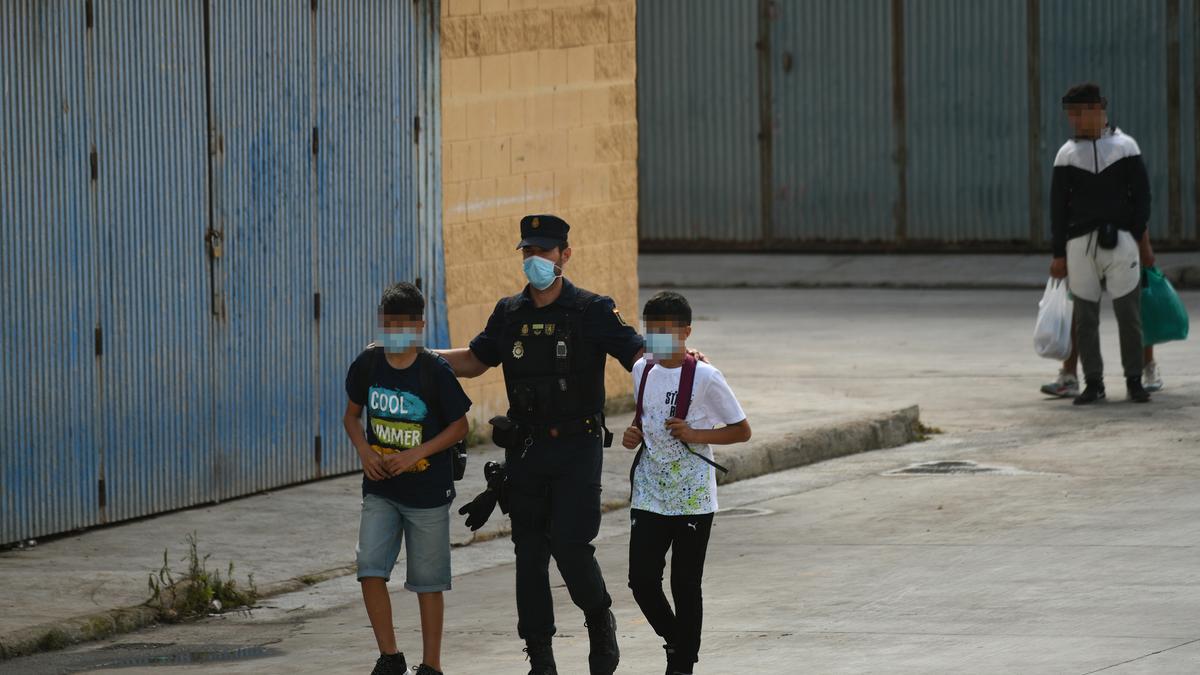 Un policía con dos menores migrantes por las calles de Ceuta.