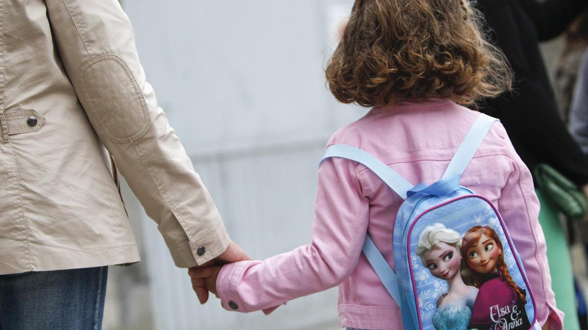 Un niña acude al colegio con su madre.