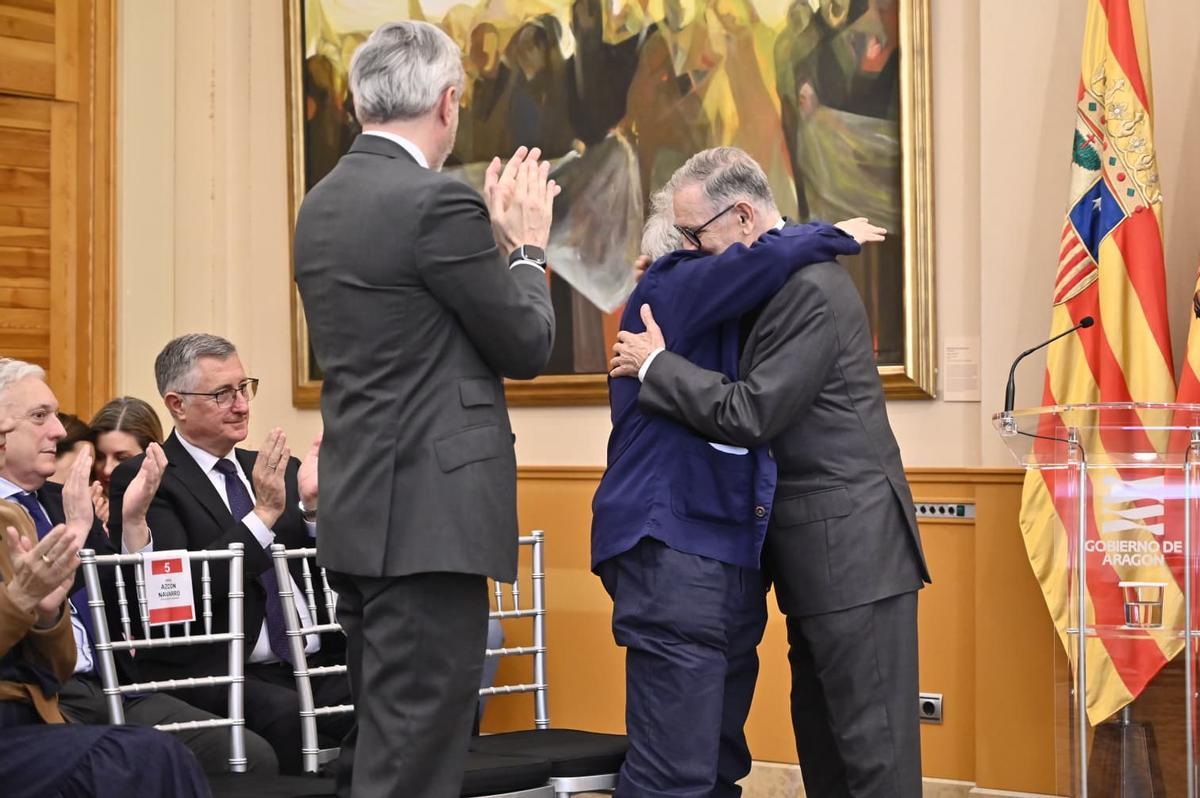 Marcelino Iglesias y Jorge Gay se abrazan, frente al aplauso de Jorge Azcón.