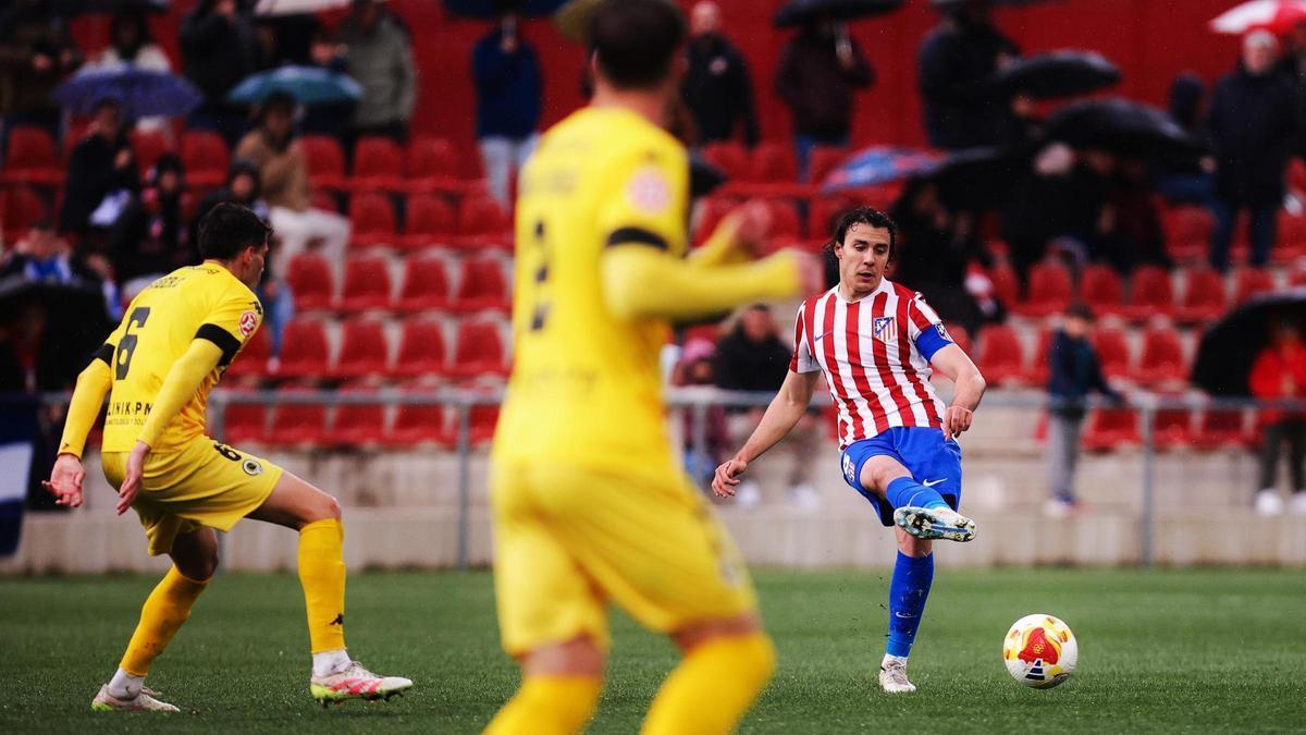 Javi Serrano, del Atlético Madrileño, golpea el balón con Roger Colomina, a la izquierda, defendiéndole.