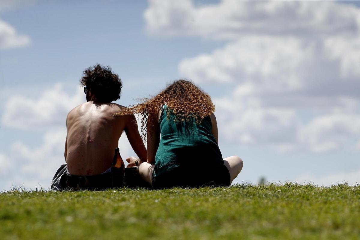 Archivo - Una pareja de jóvenes en el césped de un parque en Madrid.