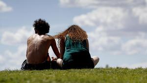 Archivo - Una pareja de jóvenes en el césped de un parque en Madrid.