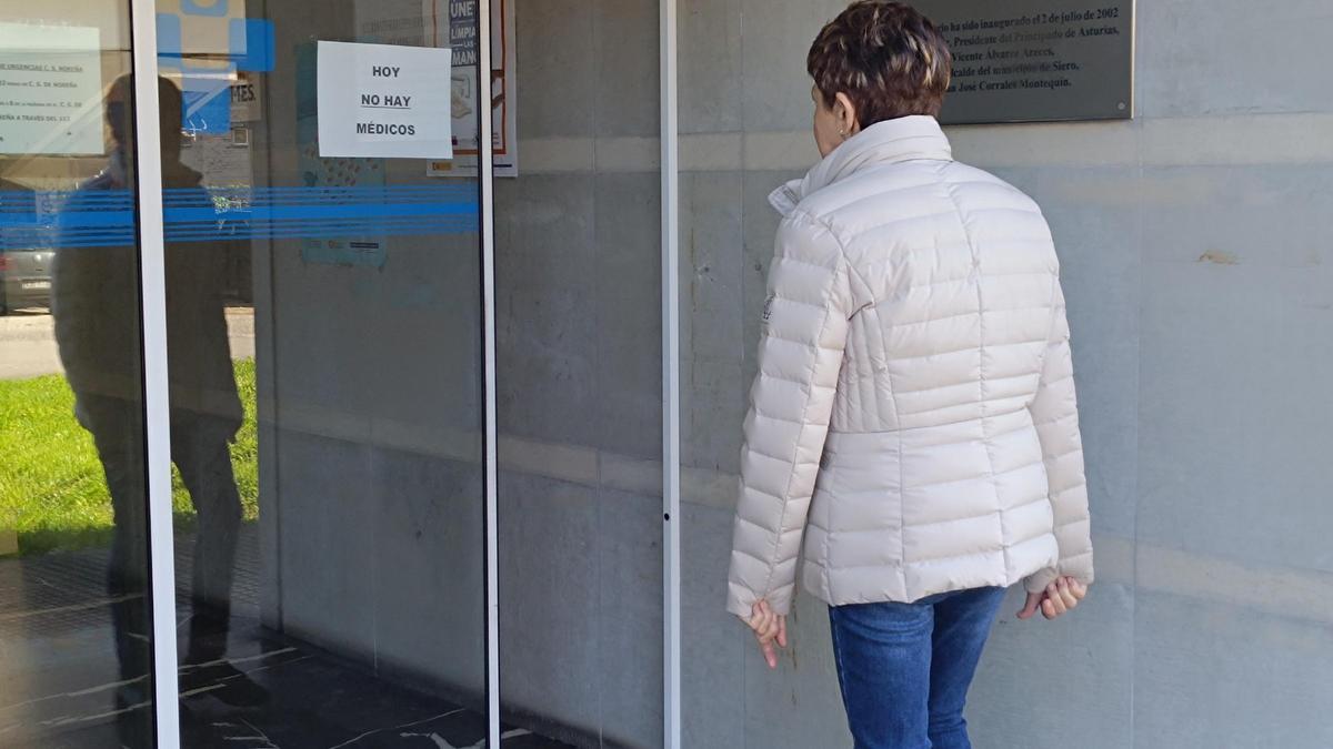 Una usuaria, leyendo el cartel en el que se advierte de que no hay médicos en el centro de salud.