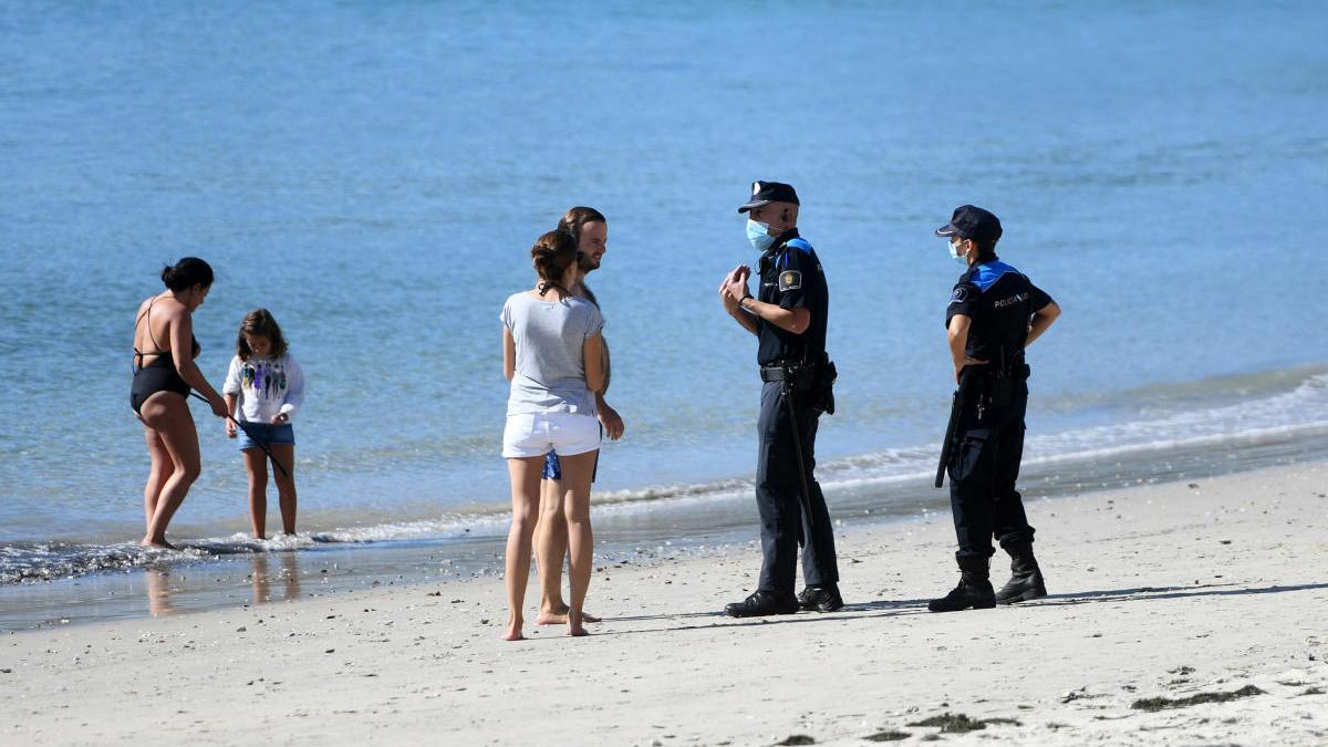 Policías alertan del uso obligatorio de mascarilla en la playa de Silgar. // Gustavo Santos