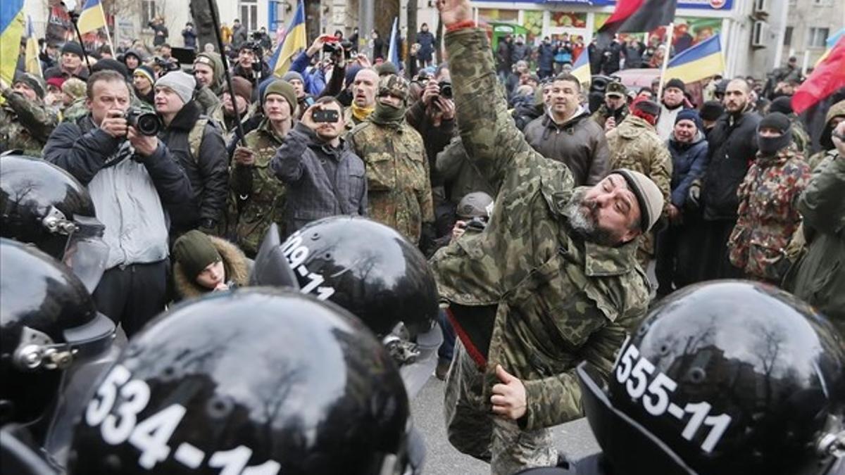 Manifestantes lanzan piedras a un banco ruso en un acto de protesta en Kiev.