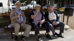 Tres jubilados descansan en un banco de un parque en Valencia.