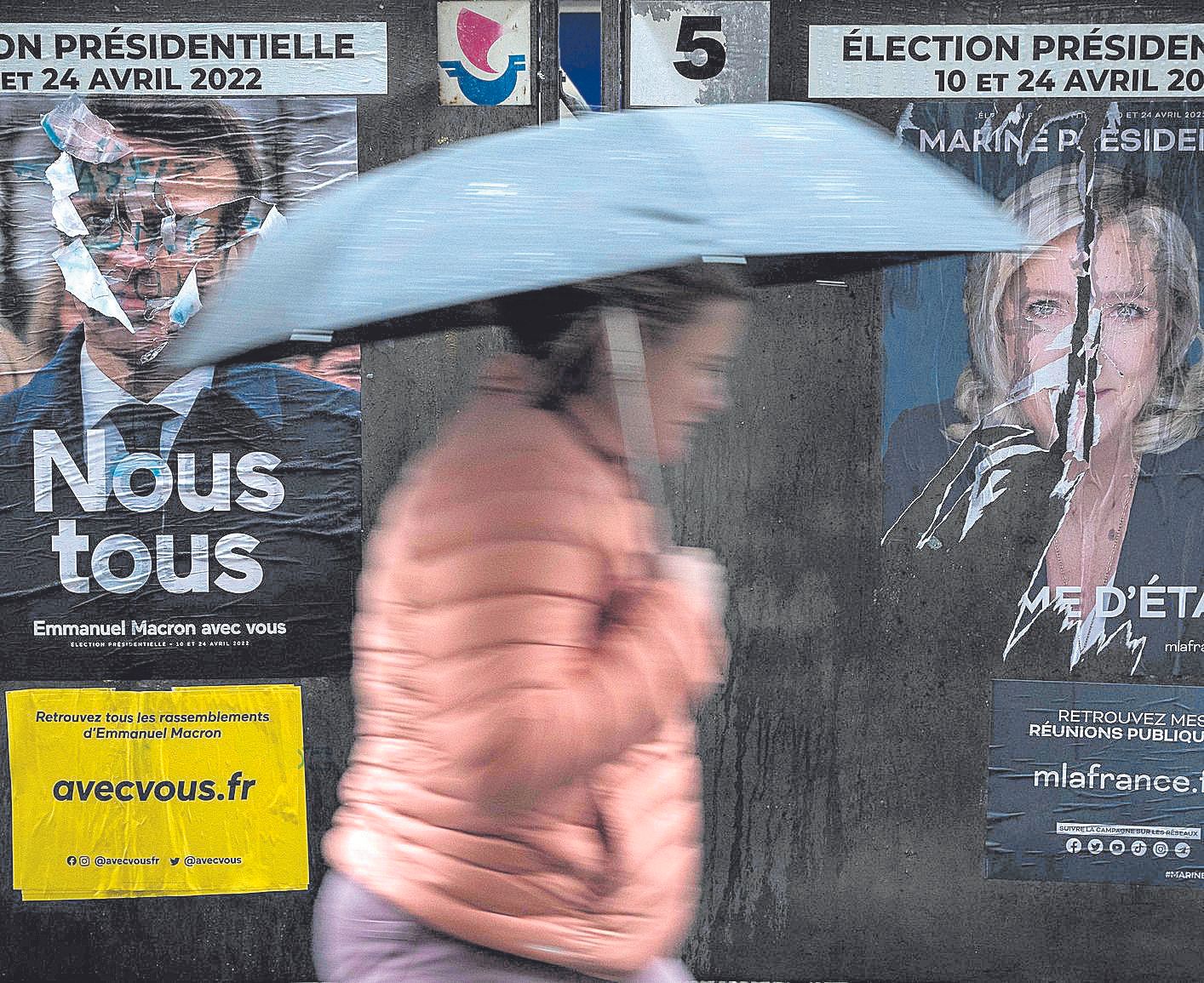 Carteles electorales de Macron y Marine Le Pen en un París bajo la lluvia.