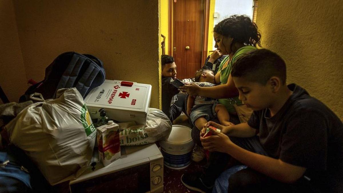 Los tres hermanos, junto a sus pertenencias, en el rellano de uno de los pisos del edificio junto a su madre, después de ser desahuciados.