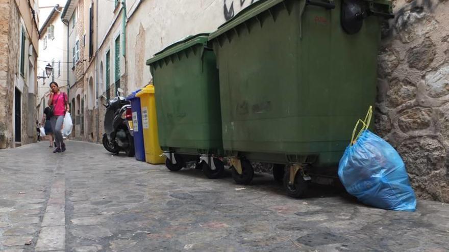 Bolsas abandonadas a plena luz del día junto a un contenedor.