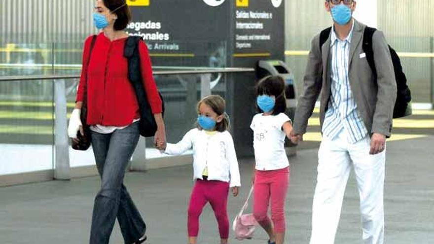 Una familia pasea por las instalaciones del aeropuerto internacional de México DF con mascarillas de protección en sus caras.