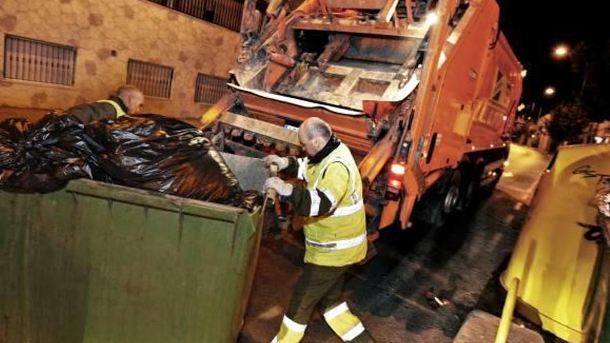 Dos operarios del servicio de basuras trabajan en el vaciado de contenedores.