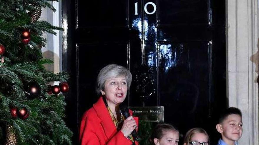 May se fotografía con unos niños ante 10 de Downing Street. // AFP