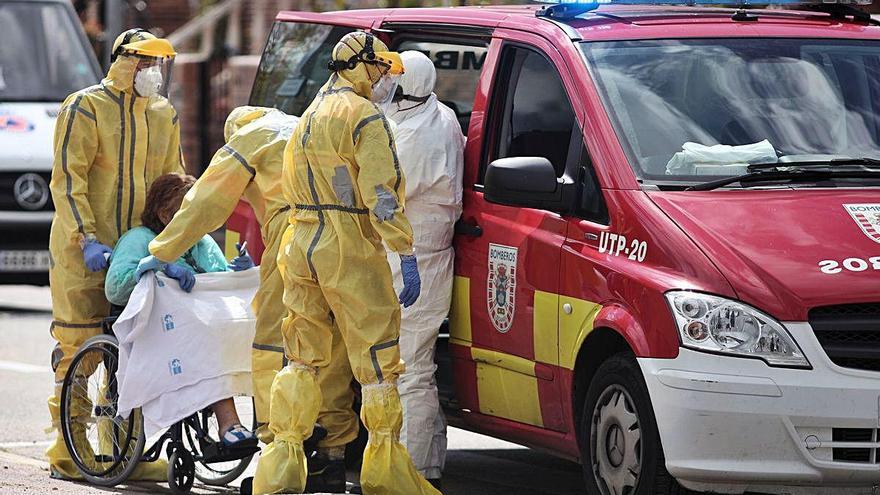 Dos bomberos de Leganés (Madrid) ayudan a trasladar a una paciente.