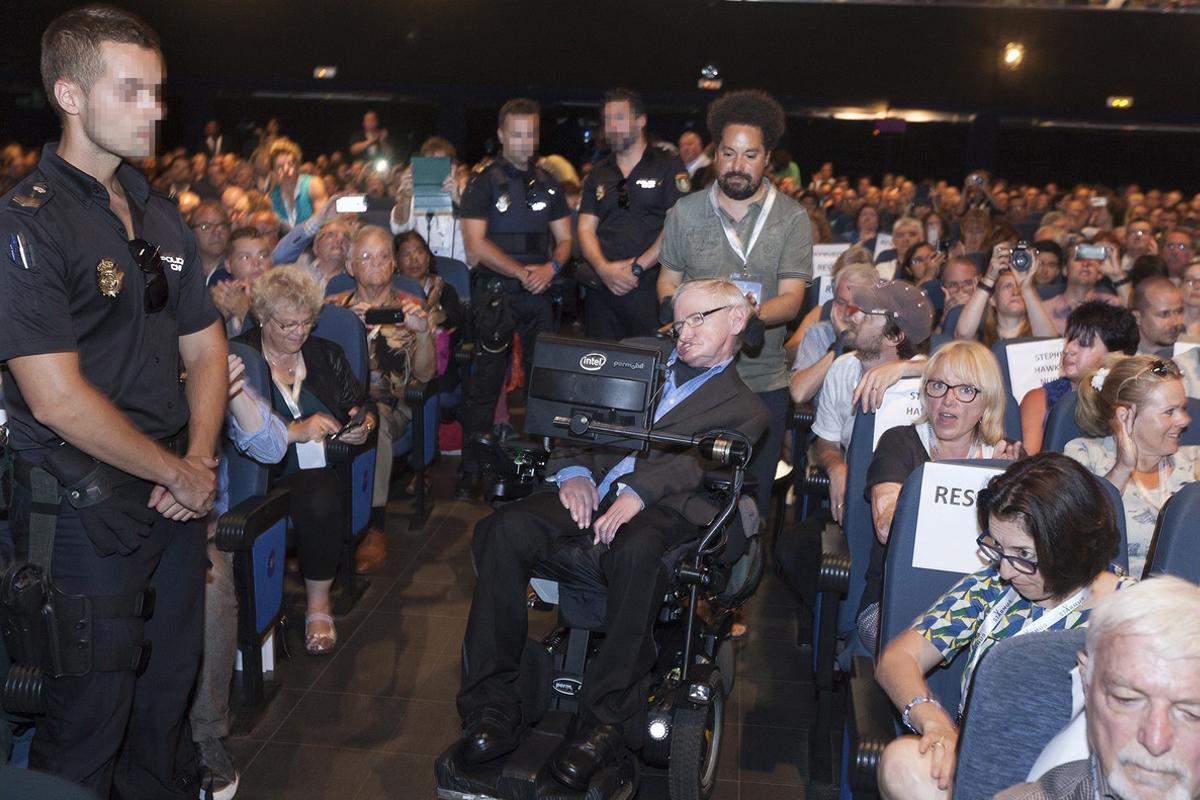 GRA059 ARONA (TENERIFE), 01/07/2016.- El físico británico Stephen Hawking custodiado por tres agentes de la Policía nacional durante su asistencia al Festival Starmus el pasado miércoles, tras recibir amenazas de muerte por parte de una mujer estadounidense que ha sido detenida en Arona (Tenerife) por supuestos delitos de acoso y amenazas al científico. EFE/Ramón de la Rocha