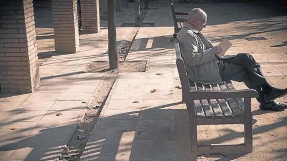 Un pensionista lee un libro en el paque Can Miralletes en Barcelona.