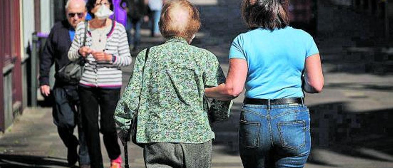 Una mujer mayor pasea junto a su cuidadora. | | A.G.