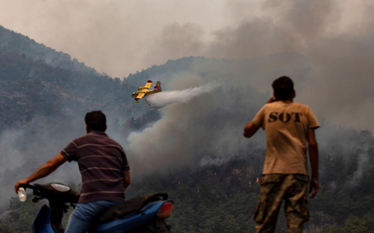 Unos vecinos del sur de Turquía observan como los hidroaviones luchan contra un incendio forestal.